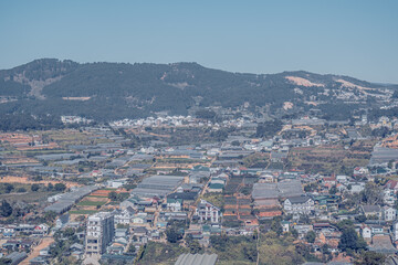 Panorama landscape, Dalat city, Langbian Plateau, Vietnam Central Highland region. Vegetable fields, many houses, architecture, farmlands, greenhouse. Mountain background. Blue Gray smoky toned photo