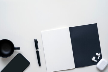 Black and white workspace with open booklet and supplies on white background.