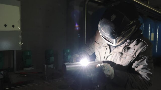 A production worker welds metal structures by argon welding