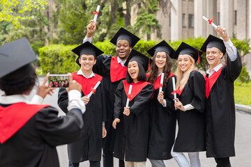 Emotional multiracial students having graduation party, taking photos
