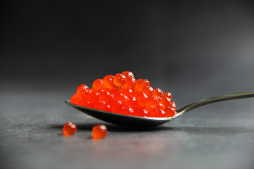 Red caviar or roe in spoon on gray background