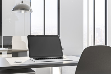 Modern laptop on black table of stylish work place in open space office with glass walls. 3D rendering