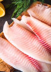Fresh raw fish tilapia fillet on a board, close-up view