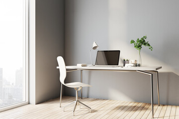 Stylish sunny work place at home with light table and chair, modern laptop and city view from big window