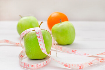 Measuring tape wrapped around two green apple and orange isolated on white background, Concept of the goal to lose weight,the goal of diet,