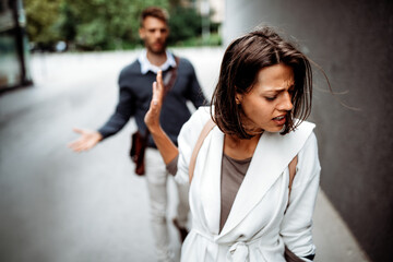 Sad young woman and man outdoor on street having relationship problems