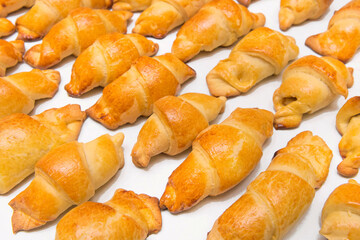 Fresh homemade baked goods. Croissants on a white isolated background. Buns on the counter at the bakery