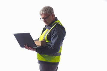 Man with laptop and a cardboard box in his hands. Concept it works in a warehouse. Warehouse worker with computer. Warehouse worker enters data from box into database. Computer foreman during work