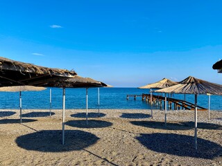 Empty beach with reed umbrellas, no one on the beach.  Beautiful blue sky, sea, sand, hot weather.  A beach without travelers and tourists.  Quarantine due to covid-19 coronavirus.