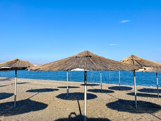Empty beach with reed umbrellas, no one on the beach.  Beautiful blue sky, sea, sand, hot weather.  A beach without travelers and tourists.  Quarantine due to covid-19 coronavirus.