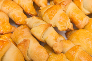 Fresh homemade baked goods. Croissants in heap background. Buns on the counter at the bakery, close up