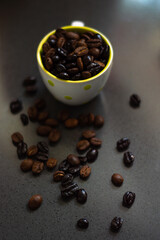 Cup of coffee with roasted coffee beans inside of different shades and kinds on a gray background. Coffee beans surrounding mug. Copy space