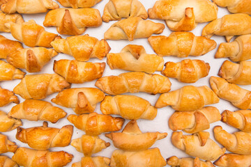 Fresh homemade baked goods. Croissants in heap on a white background, isolated. Buns on the counter at the bakery, top view