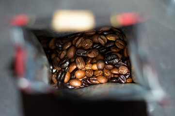 Roasted coffee beans inside a coffee packet. Focus on center of image. Variety of kinds of roasted coffee beans