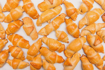 Fresh homemade baked goods. Croissants in heap on a white background, isolated. Buns on the counter at the bakery, top view