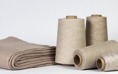 Light bobbins with thread and fabric on a white isolated background. Production concept, tailor shop.