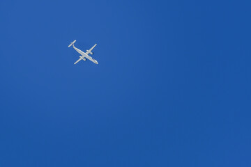 A passenger plane is flying at a high altitude against a blue sky background.