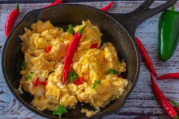 spicy scrambled eggs with chili in a cast iron pan from above