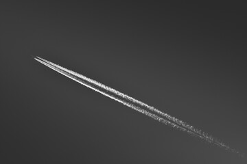 A passenger plane flies at high altitude and leaves a condensation trail behind it.