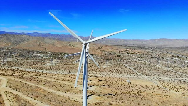 Windmills, wind turbines, aerial 4k drone slow sweep L to R, energy, green, renewable, huge power generating farm on desert hills, with Mt San Gorgonio in BG in Palm Springs, Coachella, Cabazon, Calif