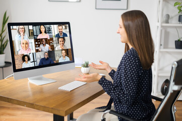 Online video discussion with many people together. Young woman sits in front of laptop with many...