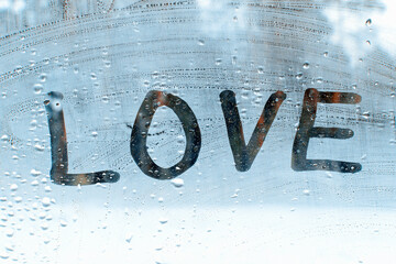 Word love on glass with raindrops.