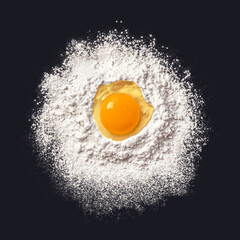 Egg in flour. Dough preparation. Black background. View from above.
