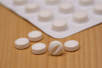 White pills on the table and blister pack. Selective focus.
