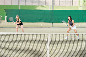 two young girls playing tennis together, tennis players waiting for the serve