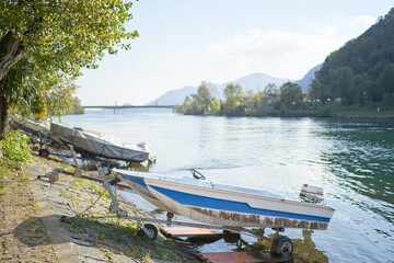 Docked boats on the lake Como district in Italy on sunny day. Alp mountains on background
