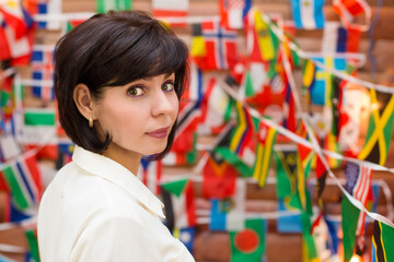 Brunette woman looking over her shoulder back against a background of different flags.