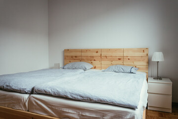 Fototapeta na wymiar Stone pine bed: Empty wooden bed with pillow and blanket