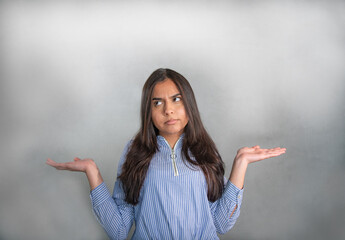 Doubting young woman in blue striped jersey,  elbows bent, arms raised and palms up. Questioning...