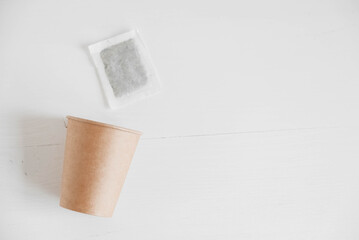 Paper cup and square dry tea bag on a white background. Top view. Copy, empty space for text