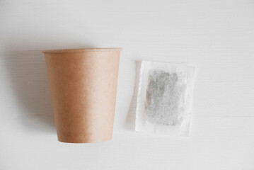 Paper cup and square dry tea bag on a white background. Top view. Copy, empty space for text