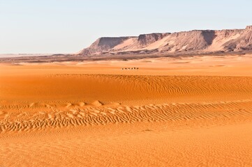Fototapeta na wymiar Impression von einer Saharaexpedition - Wunderschöne Saharalandschaft mit einer Karawane in der Ferne - Sand, Stille, Einsamkeit und endlose Weite