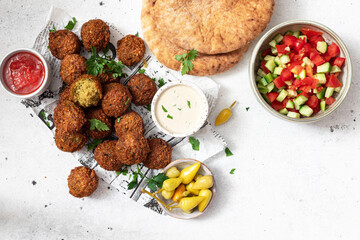 Traditional homemade chickpea Falafel balls with vegetables salad , hummus, tahini sauce, hot peppers and pita bread. Vegetarian food concept.