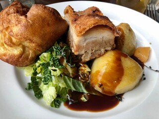 Traditional british Sunday roast, pork belly with potato and gravy