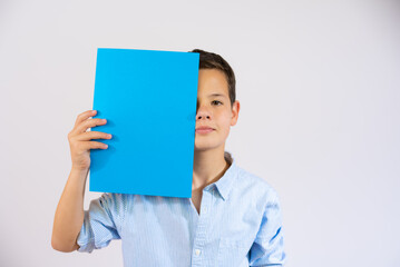 Cute boy holding blue blank paper covering eye isolated over white background