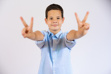 Cute boy in casual shirt showing victory sign isolated over white background