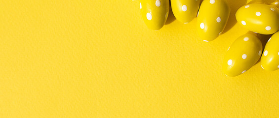 Fototapeta na wymiar Easter concept banner. Yellow eggs with white polka dots on a yellow background. Easter background with copy space. Minimalism.
