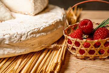 Cheese Camambert with raspberry basket. Rustic set on black backdrop. Healthy fresh nutrition. Healthy food background.