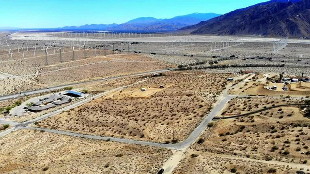Fly in across barren desert part 2, interstate freeway, windmills, wind turbines energy, green, renewable, huge power generating farm, Palm Springs, Coachella Valley, aerial 4k drone, Cabazon, Calif