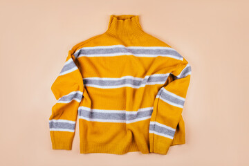 Trendy fall fashion flatlay with a yellow striped sweater isolated on beige.