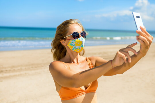 Funny Girl Taking Selfie Photo By Smartphone On Tropical Sea Beach. New Rules To Wear Cloth Face Covering Mask At Public Places Due Coronavirus COVID 19. Family Holidays With Children, Summer Travel.