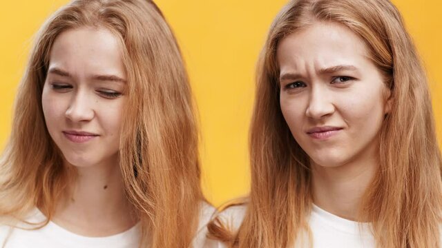 Two displeased redhaired twin sisters looking at camera with discontent, frowning faces and shaking heads in denial