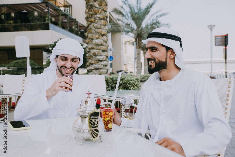 Wall mural Two young businessmen going out in Dubai. Friends wearing the kandura traditional male outfit in Marina