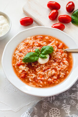 Tomato soup with rice decorated by cream and basil leaf.