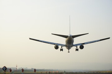 Fototapeta na wymiar Airplane landing on runway at the airport - 着陸する飛行機 後ろ姿 飛行場 