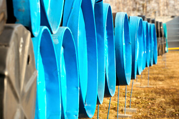 Large-diameter pipes with plugs lie in an open warehouse on a summer day.